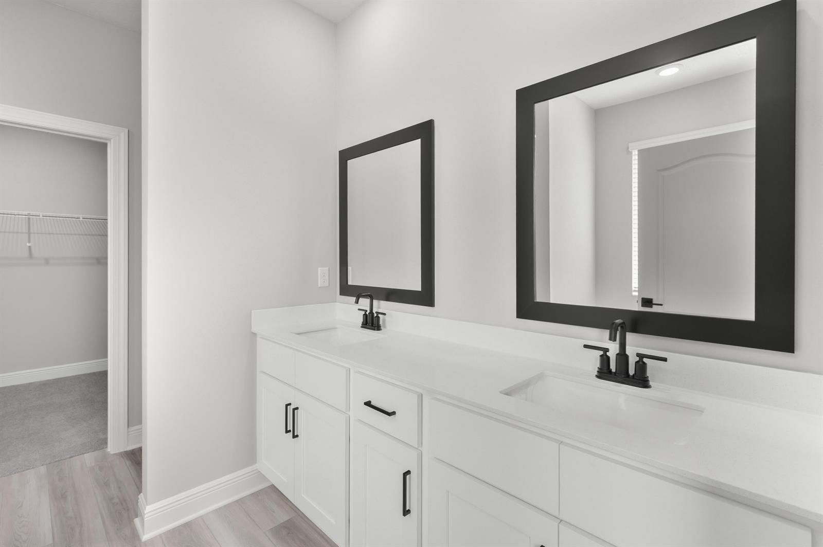 A modern bathroom features a white double vanity with black hardware and matching framed mirrors — 9345 101st Avenue, Vero Beach FL 32967, VERO BEACH, FL
