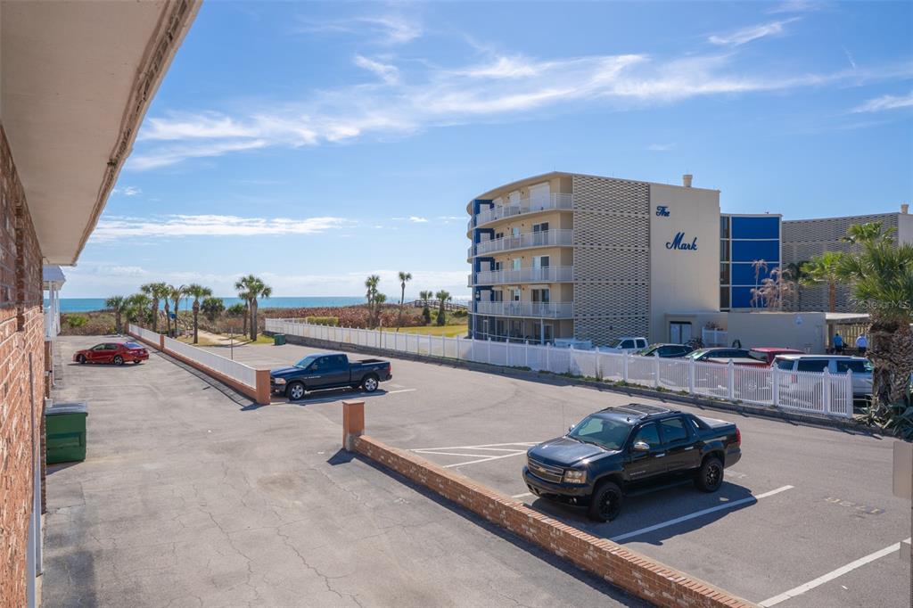 An elevated view of a parking lot with vehicles and a beachside apartment building — 5000 OCEAN BEACH BOULEVARD UNIT B11, COCOA BEACH, FL