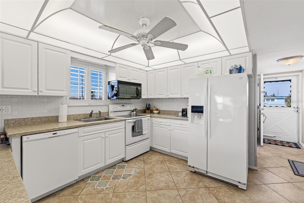 A kitchen with white cabinets, granite countertops, tile flooring, and a ceiling fan — 5000 OCEAN BEACH BOULEVARD UNIT B11, COCOA BEACH, FL