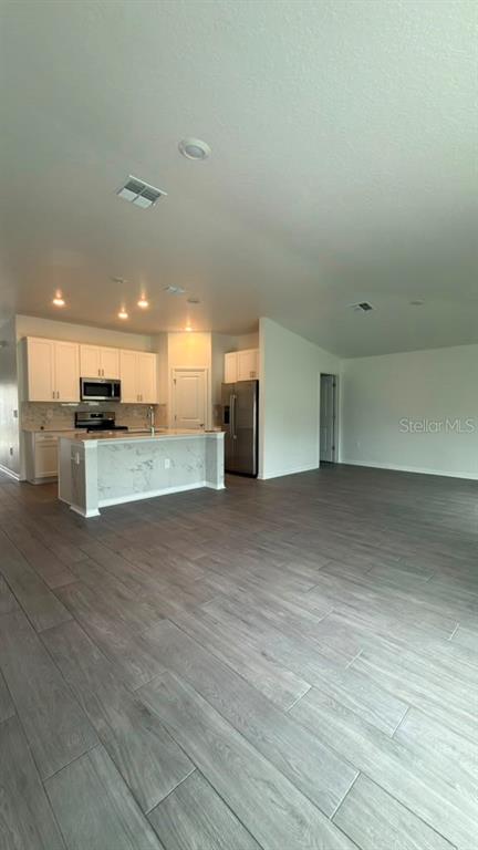A kitchen with white cabinets, a marble-patterned island, and light wood-look tile flooring — 707 GROVE STREET, WINTER HAVEN, FL