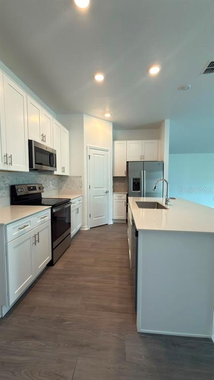 A modern kitchen features white cabinetry, stainless steel appliances, and a large central island — 707 GROVE STREET, WINTER HAVEN, FL