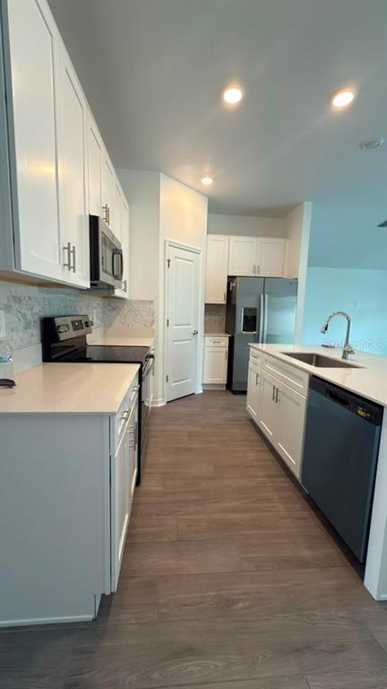 A kitchen features white cabinets, stainless steel appliances, a kitchen island, and wood-look flooring — 707 GROVE STREET, WINTER HAVEN, FL