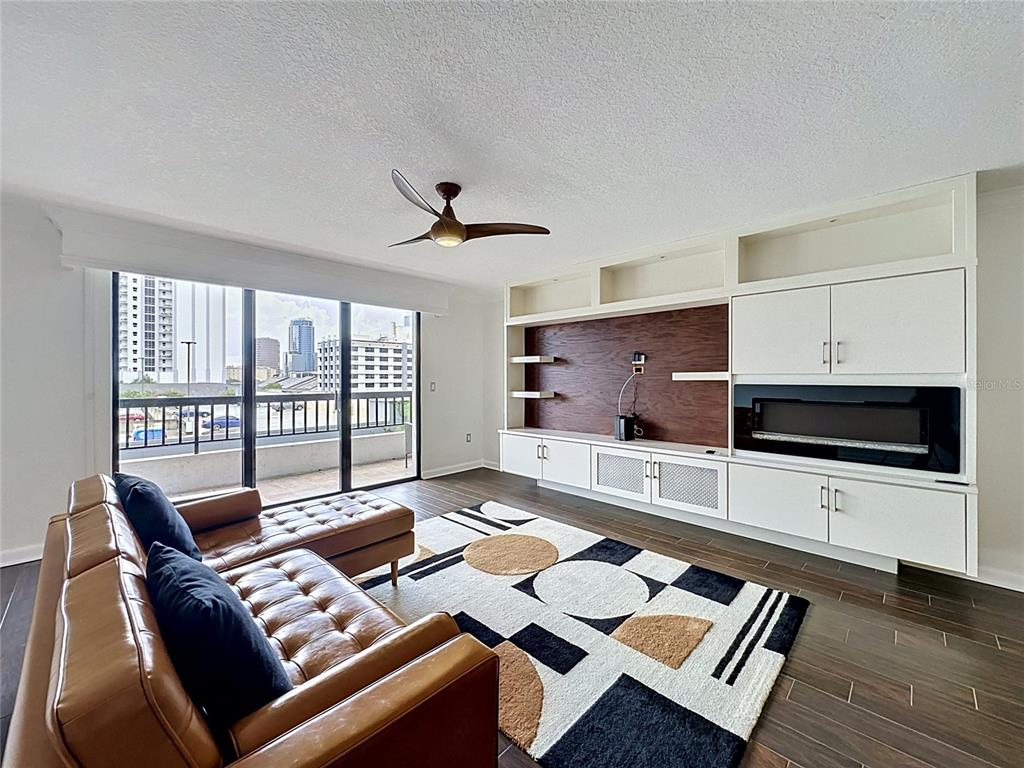 A living room features a leather sectional, geometric rug, built-in cabinetry, and a balcony view — 530 E CENTRAL BOULEVARD UNIT 604, ORLANDO, FL