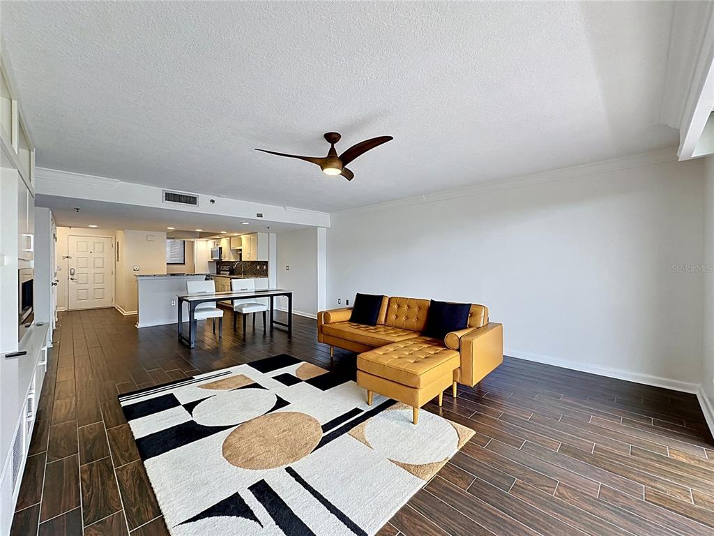 A living room with a tan sectional, patterned rug, and dining area on dark flooring — 530 E CENTRAL BOULEVARD UNIT 604, ORLANDO, FL
