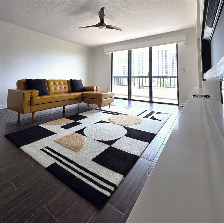 A living room features a yellow tufted sofa, a geometric rug, and a sliding glass door — 530 E CENTRAL BOULEVARD UNIT 604, ORLANDO, FL