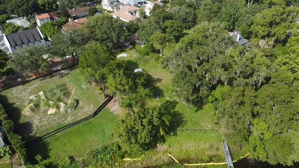 An aerial view shows a vacant, grassy residential lot with mature trees and waterfront access — 1415 GROVE TERRACE, WINTER PARK, FL
