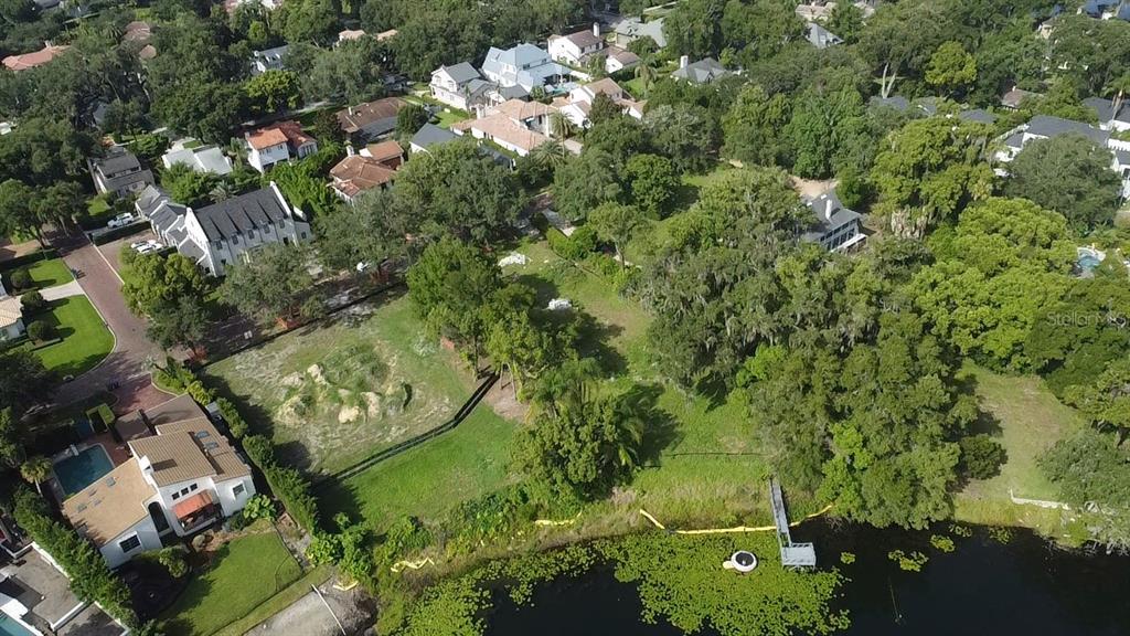 An aerial view shows a vacant waterfront lot surrounded by trees and residential houses — 1415 GROVE TERRACE, WINTER PARK, FL
