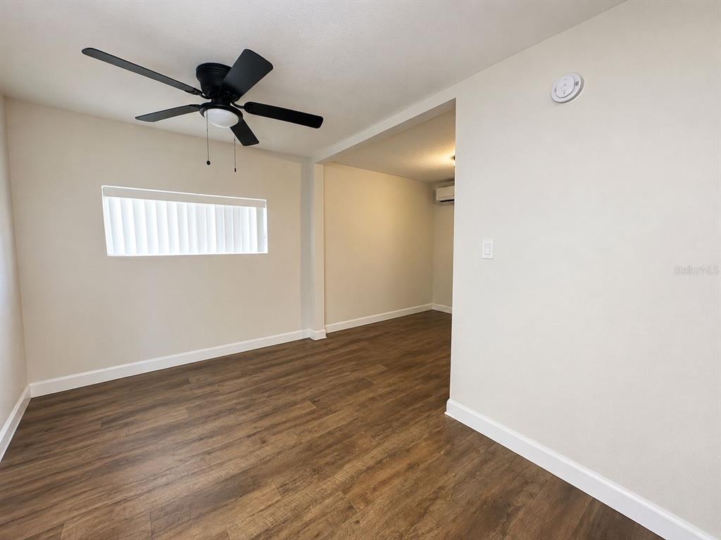 An empty room features wood-look flooring, a ceiling fan, and an adjacent open space — 129 E CONCORD STREET UNIT 5, ORLANDO, FL