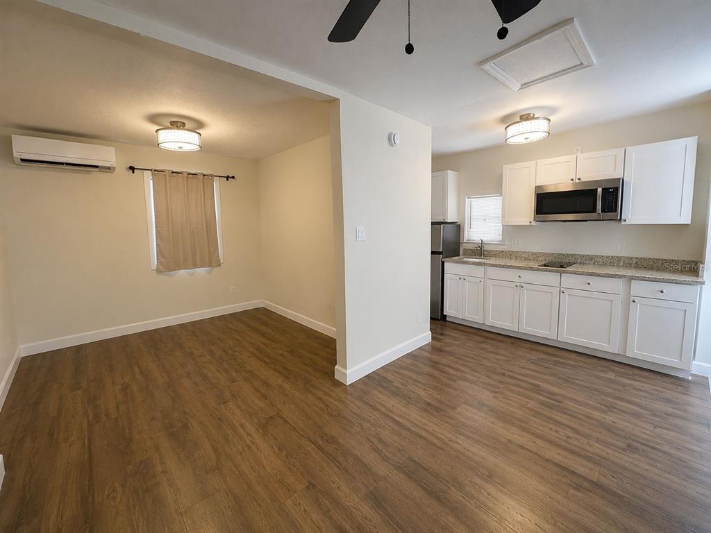A kitchen with white cabinets and stainless steel appliances opens into a dining area — 129 E CONCORD STREET UNIT 5, ORLANDO, FL