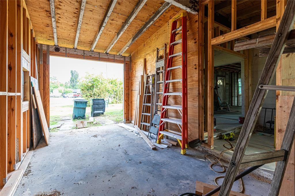 An unfinished garage space features exposed wood framing, a concrete floor, and two ladders — 4867 LOS RIOS STREET, NORTH PORT, FL