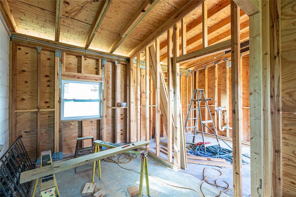 An unfinished room under construction features exposed wood wall studs, plywood sheathing, and a ladder — 4867 LOS RIOS STREET, NORTH PORT, FL