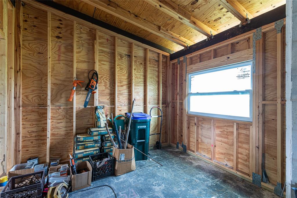 An unfinished room with exposed wood wall studs, plywood sheathing, and a single window — 4867 LOS RIOS STREET, NORTH PORT, FL
