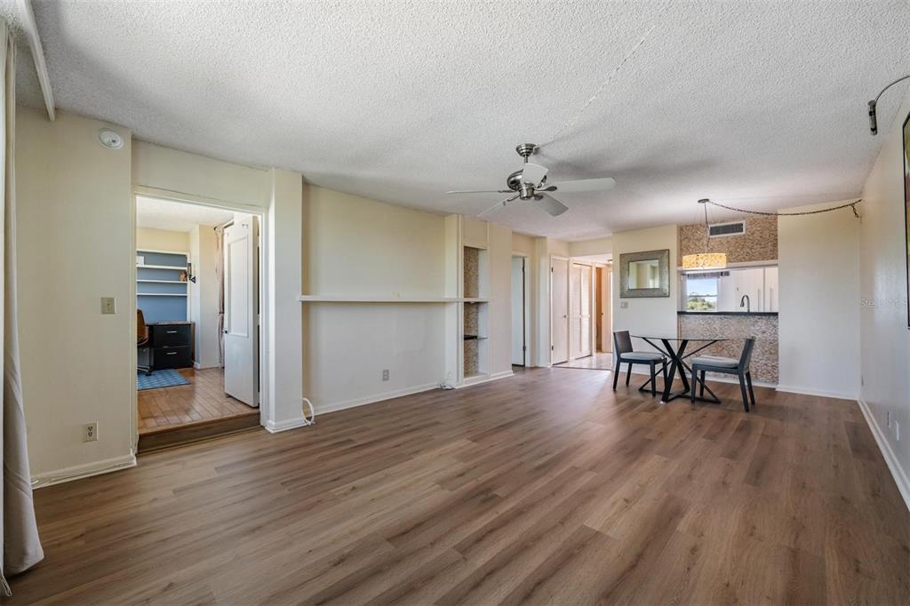An open-concept living and dining area features wood-look flooring, a ceiling fan, and built-in shelving — 2621 COVE CAY DRIVE UNIT 606, CLEARWATER, FL