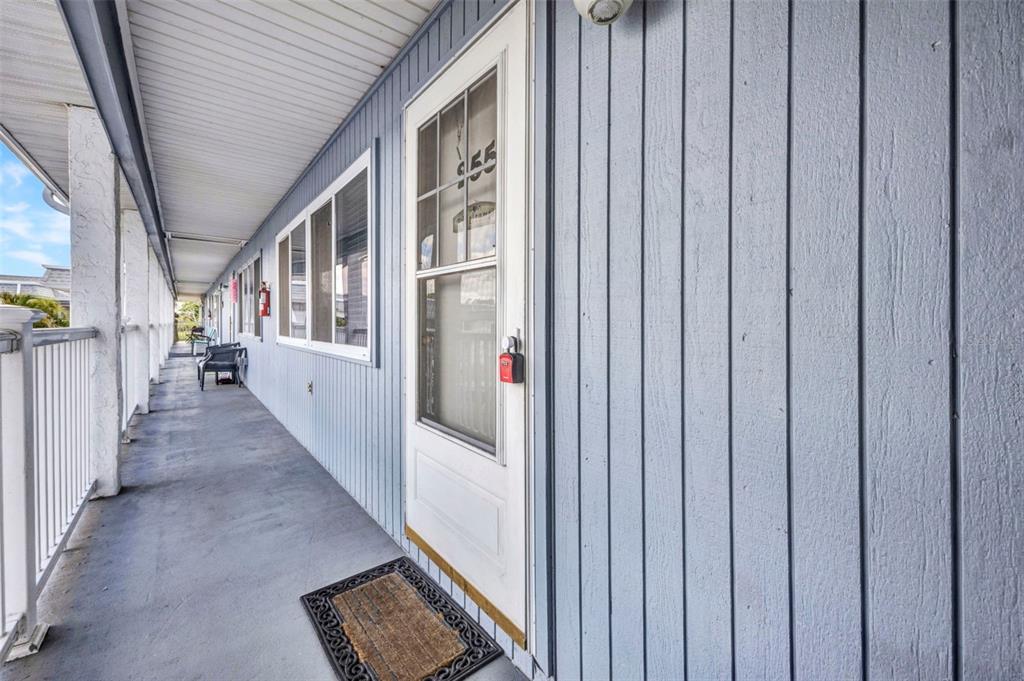 An exterior view of a covered balcony with blue vertical siding and a white door — 22375 EDGEWATER DRIVE UNIT 255, PUNTA GORDA, FL