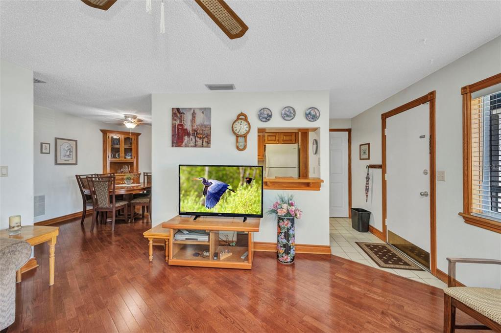 A living room with hardwood floors, a television on a stand, and an adjacent dining area — 22375 EDGEWATER DRIVE UNIT 255, PUNTA GORDA, FL