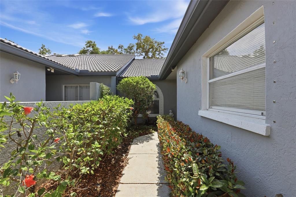 An exterior view of a home entrance with a sliding glass door and a skylight — 5721 CASA DEL SOL BOULEVARD UNIT 3223, SARASOTA, FL