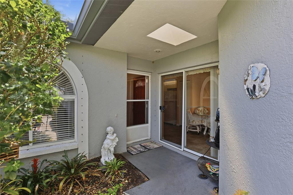 A concrete walkway leads to the front entrance of a house with gray stucco walls — 5721 CASA DEL SOL BOULEVARD UNIT 3223, SARASOTA, FL