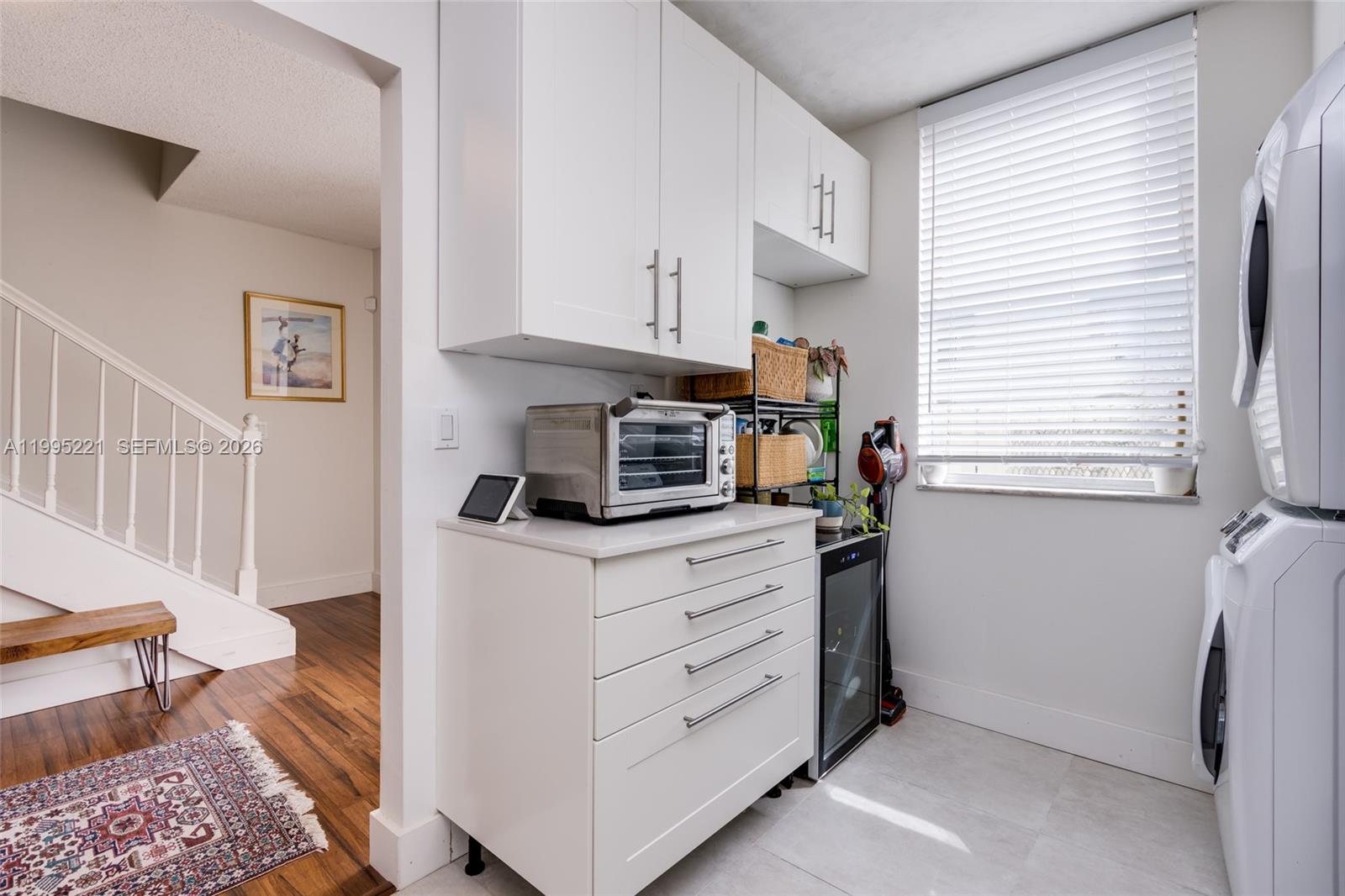 A laundry room features white cabinetry, a countertop appliance, a wine cooler, and a window — 1651 NE 115th St # 28C, Miami FL 33181, MIAMI, FL