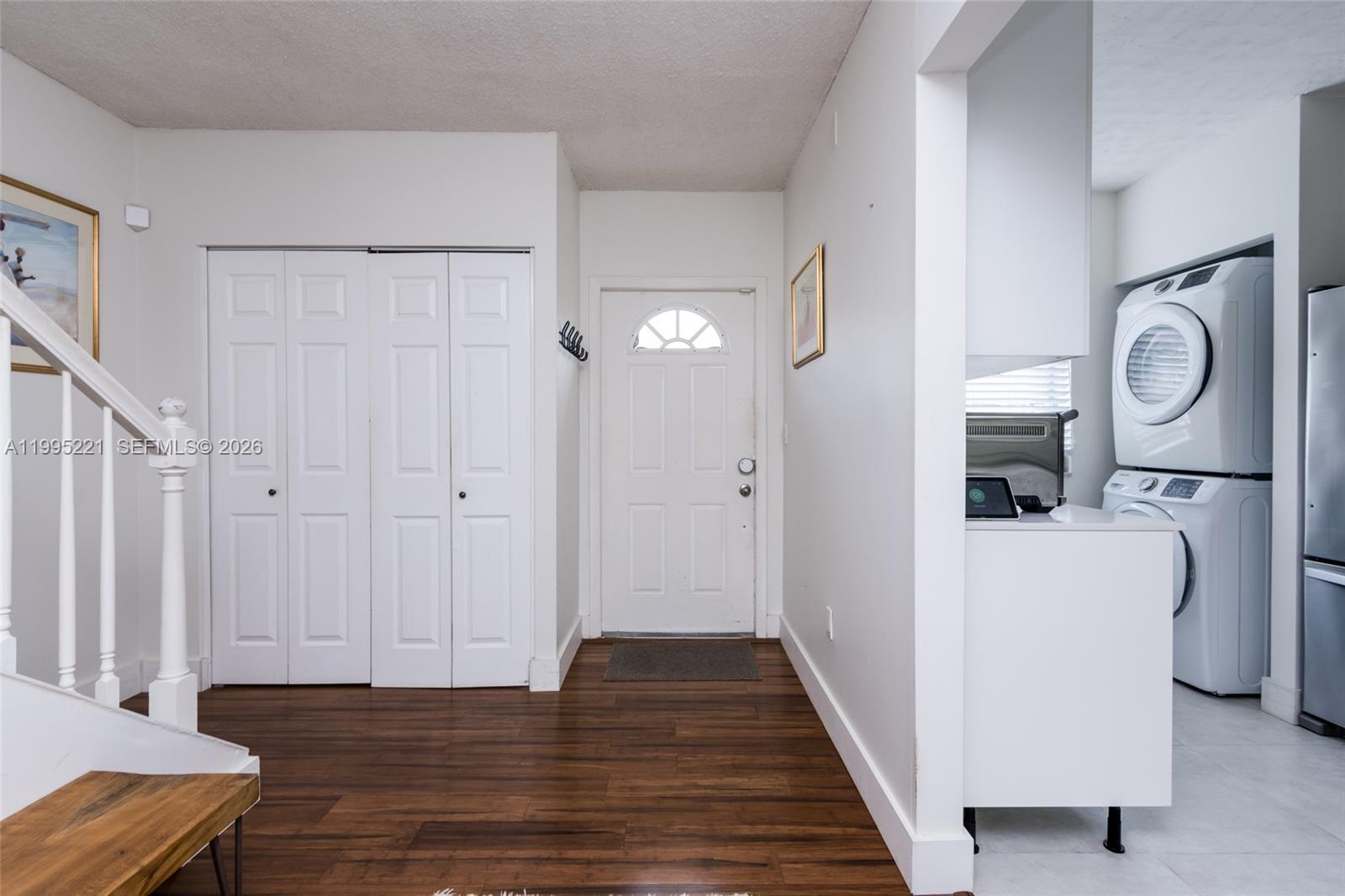 An entryway with wood flooring, a white front door, a closet, and a laundry area — 1651 NE 115th St # 28C, Miami FL 33181, MIAMI, FL