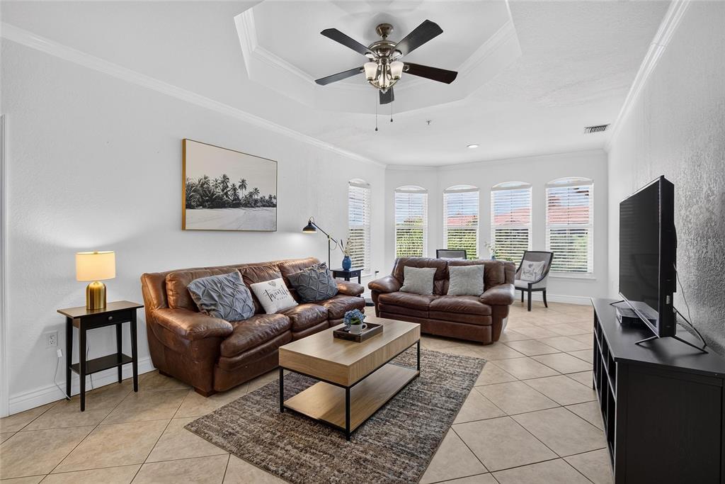 A living room features a brown leather sofa set, a coffee table, and a tray ceiling — 2723 VIA CAPRI UNIT 832, CLEARWATER, FL