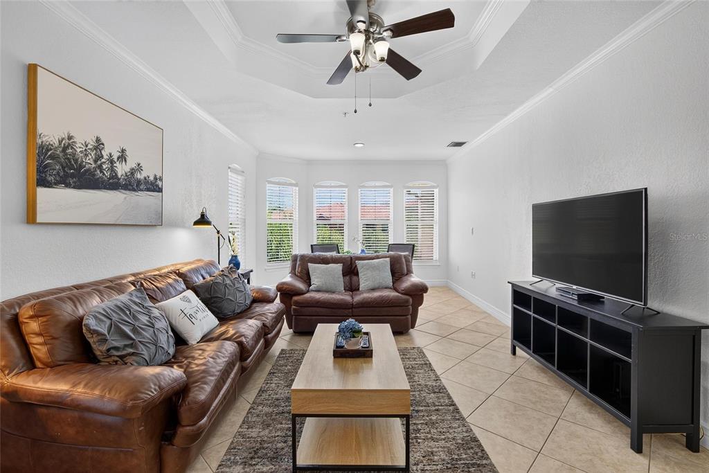 A living room features a brown leather sofa, a coffee table, and a television console — 2723 VIA CAPRI UNIT 832, CLEARWATER, FL