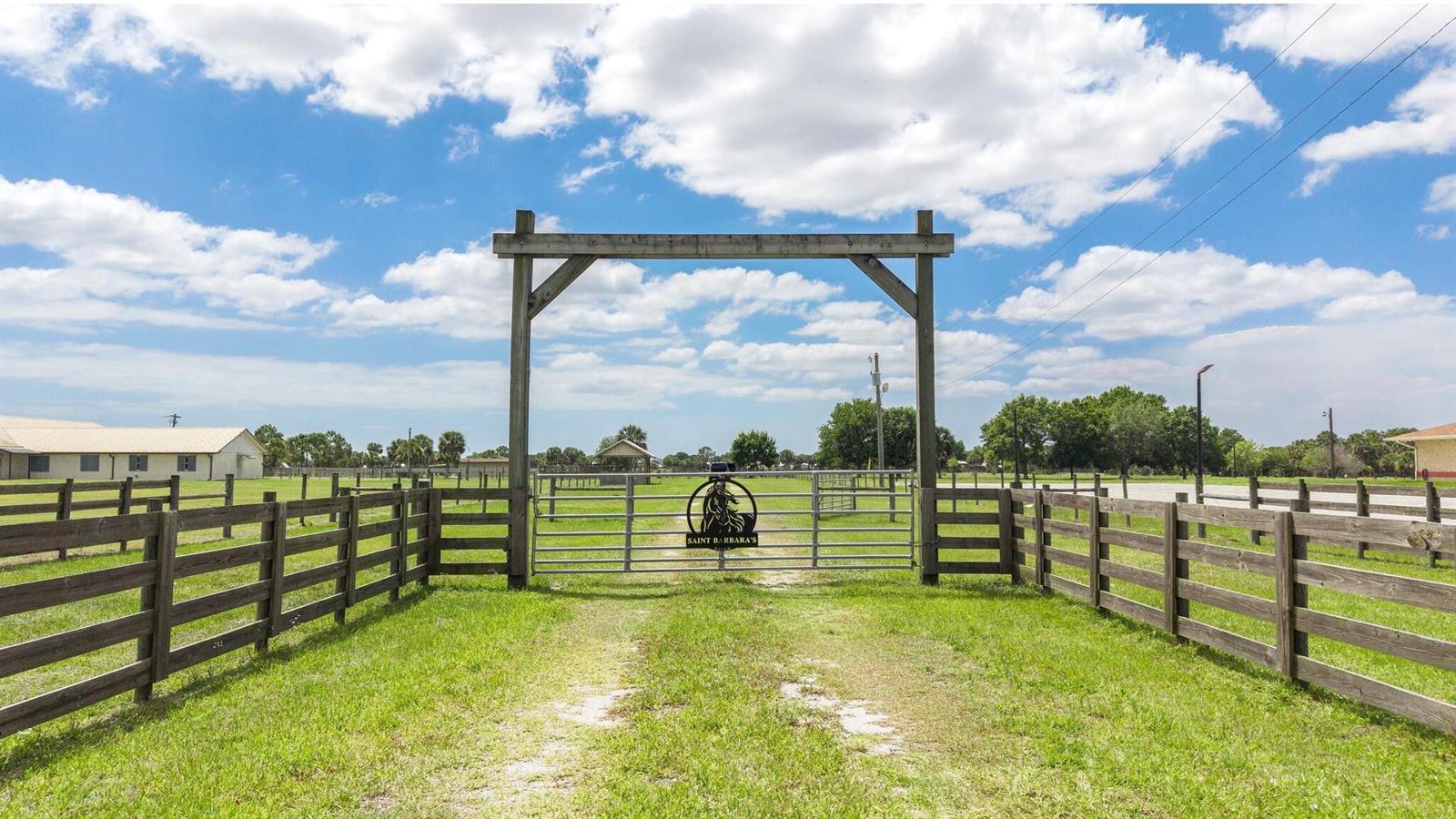 A wooden gate frame stands over a metal gate with a horse silhouette sign — 8164 Highway 70 W, Okeechobee FL 34972, OKEECHOBEE, FL