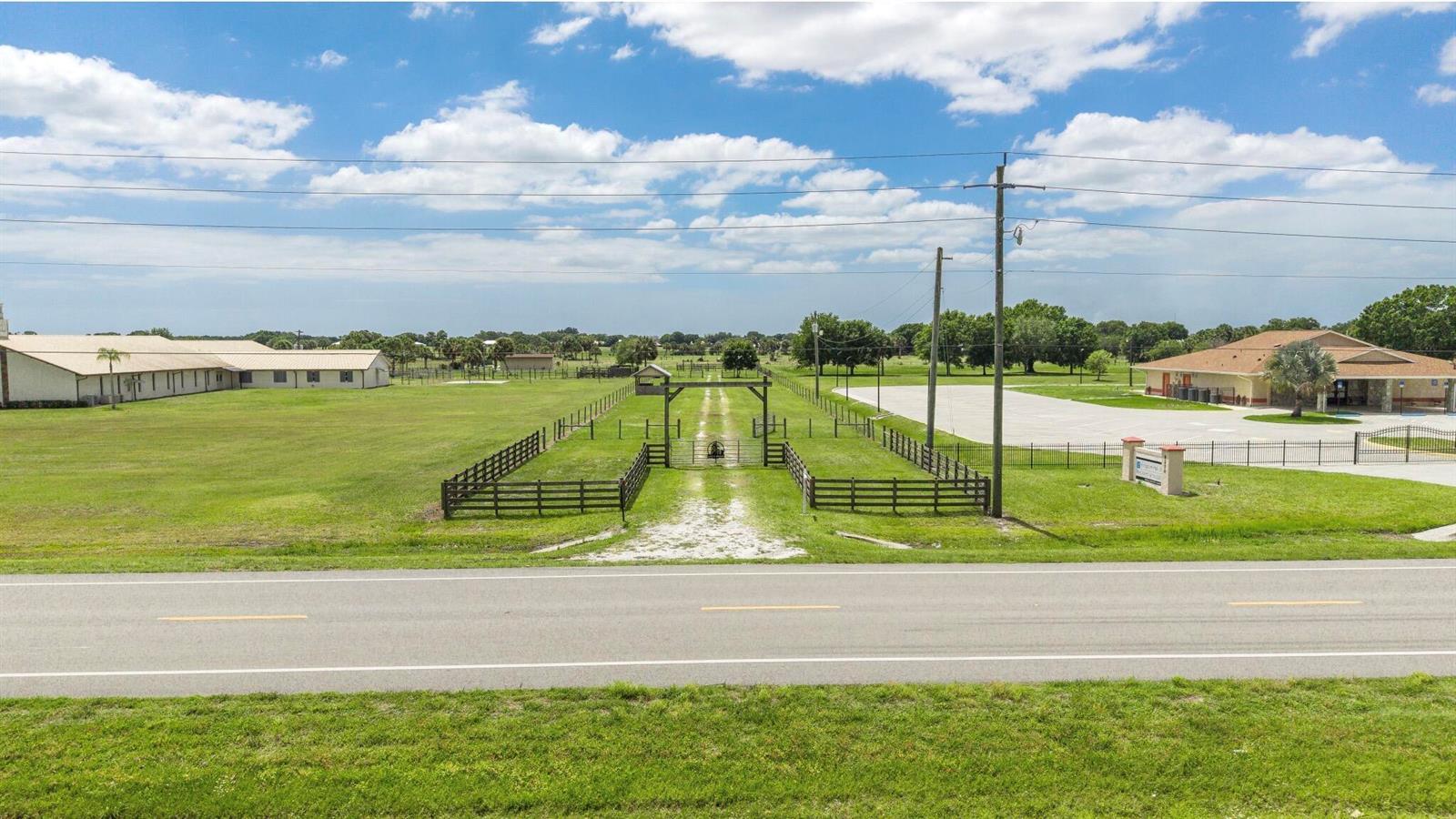 An aerial view shows a rural property with a road, fenced pasture, and two buildings — 8164 Highway 70 W, Okeechobee FL 34972, OKEECHOBEE, FL