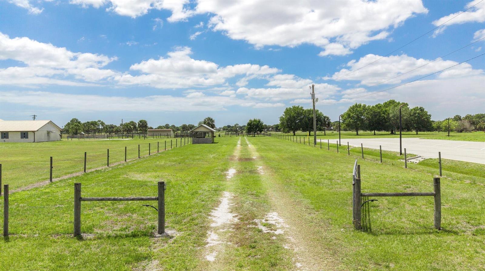 A dirt path leads through a fenced grassy field toward a small wooden structure — 8164 Highway 70 W, Okeechobee FL 34972, OKEECHOBEE, FL