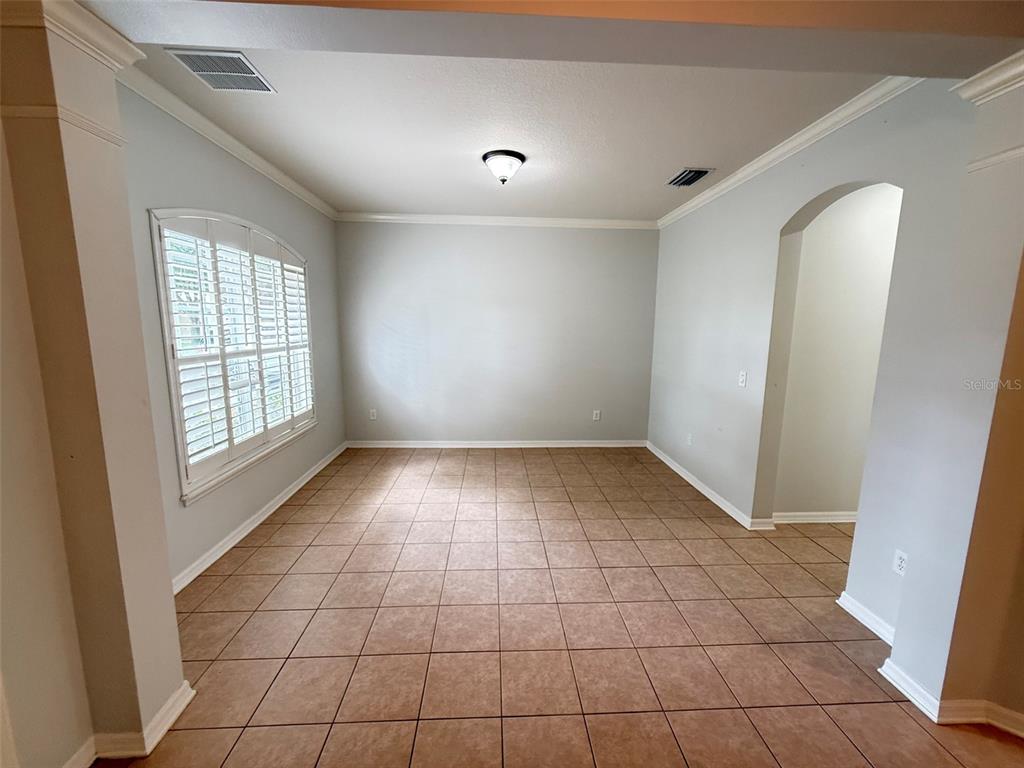 An empty room with light gray walls, tile flooring, and an arched entryway — 8523 NORTHTON GROVES BOULEVARD, ODESSA, FL