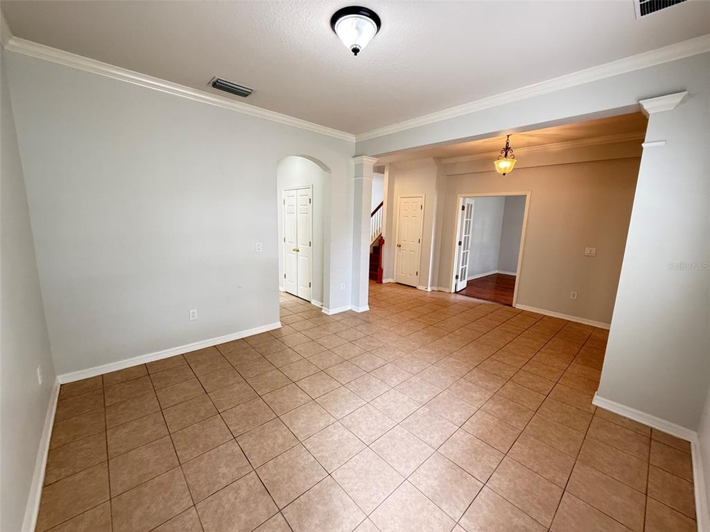 An empty room with light gray walls, tile flooring, and multiple doorways leading to other areas — 8523 NORTHTON GROVES BOULEVARD, ODESSA, FL