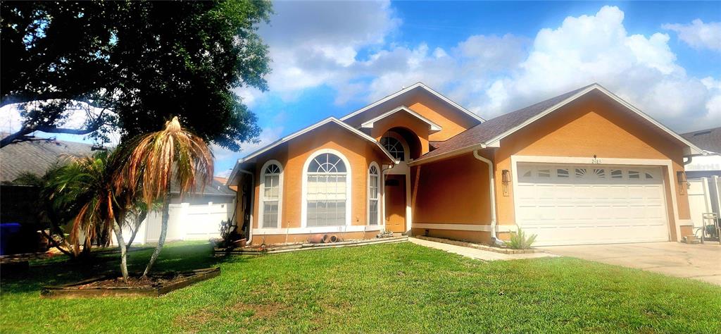 A single-story house with orange stucco walls, a shingled roof, and palm trees in front — 2483 SHELBY CIRCLE, KISSIMMEE, FL