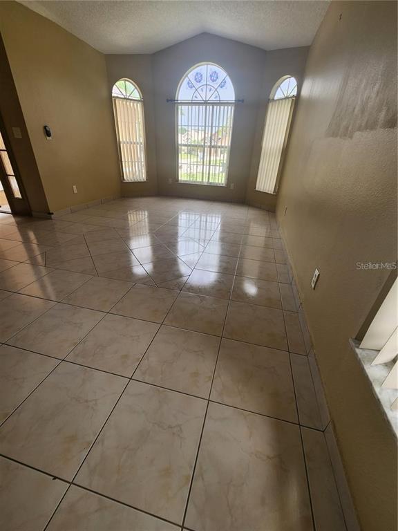 A living room with vaulted ceilings, tile flooring, a ceiling fan, and large arched windows — 2483 SHELBY CIRCLE, KISSIMMEE, FL