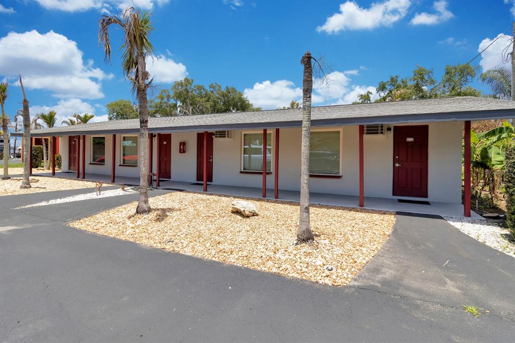 A single-story motel building with red doors, a gravel front yard, and palm trees — 6264 ALLIGATOR LAKE SHORE E, ST CLOUD, FL