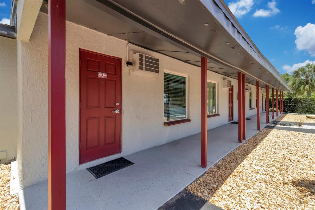 A row of motel-style rooms with red doors and windows under a covered walkway — 6264 ALLIGATOR LAKE SHORE E, ST CLOUD, FL