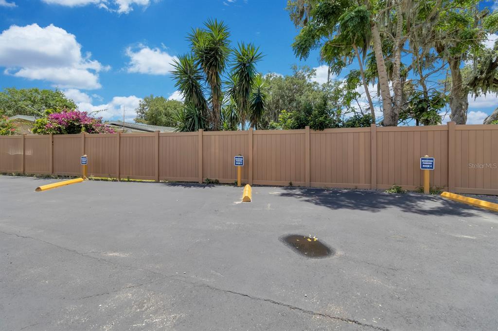 A paved parking area features three reserved spaces marked by signs against a tan fence — 6264 ALLIGATOR LAKE SHORE E, ST CLOUD, FL