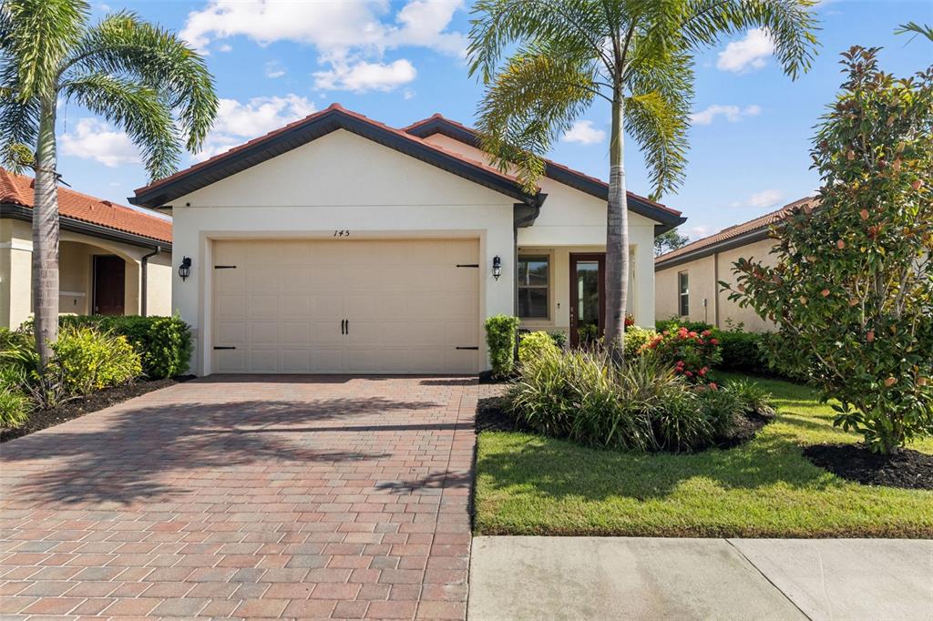 A single-story house with a beige garage, brick driveway, and palm trees under a blue sky — 145 SOLIERA STREET, NORTH VENICE, FL