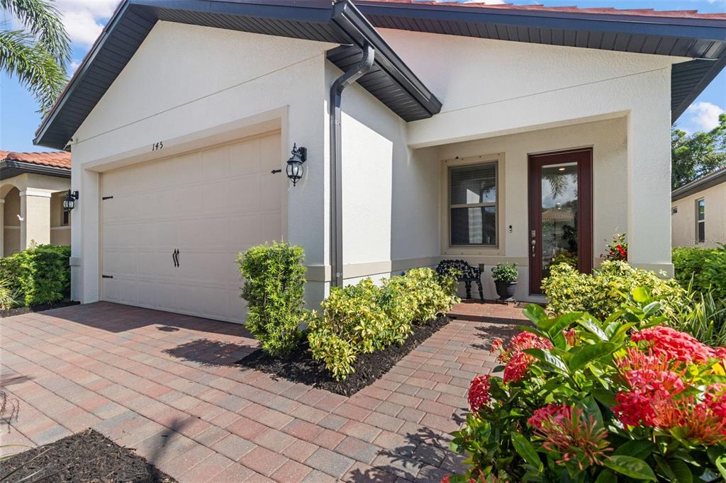 A single-story house exterior features a garage, a paved driveway, and a landscaped front entrance — 145 SOLIERA STREET, NORTH VENICE, FL