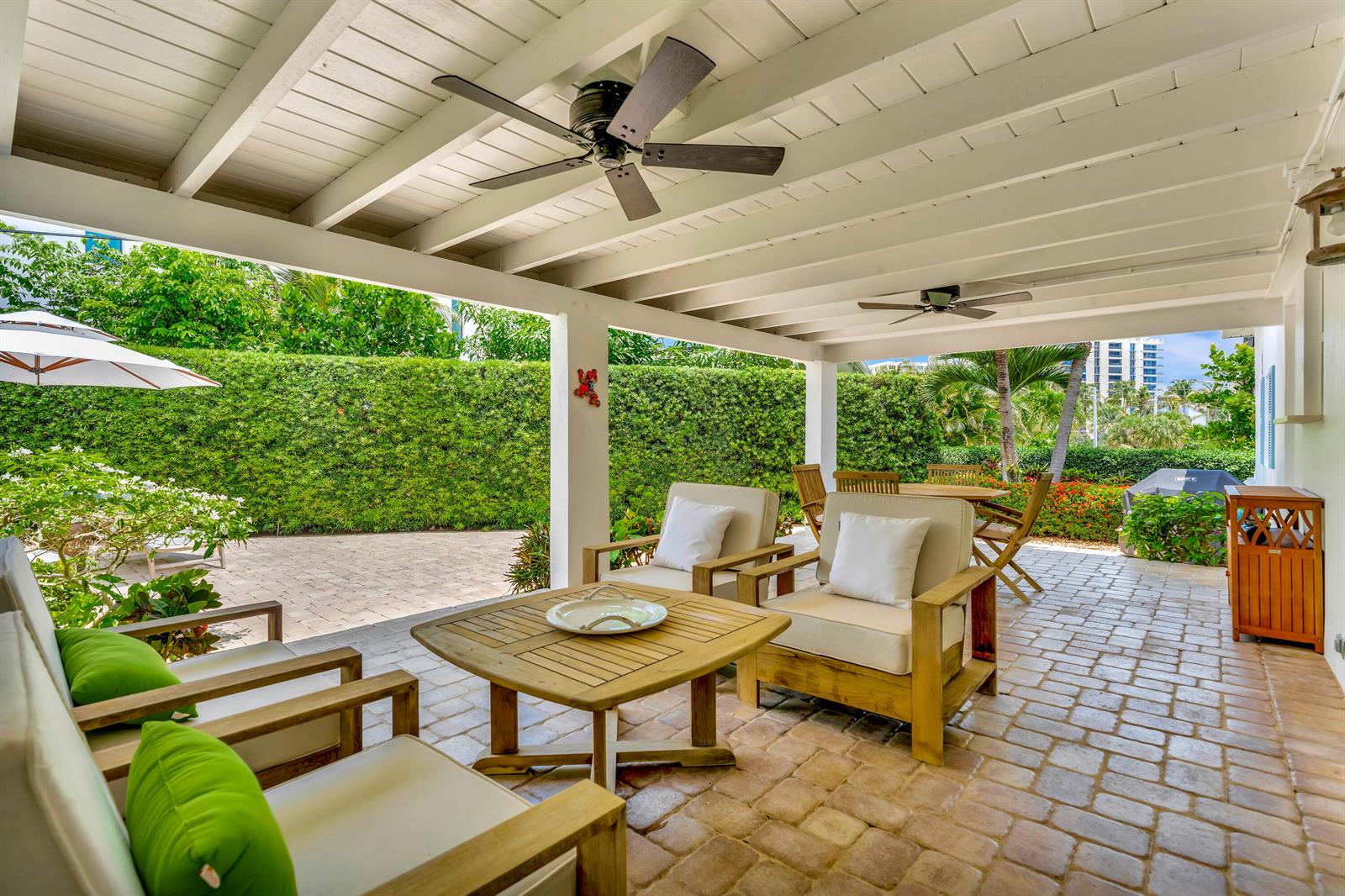 A covered outdoor patio with wood furniture, ceiling fans, and a brick floor — 333 Ocean Drive, Juno Beach FL 33408, JUNO BEACH, FL