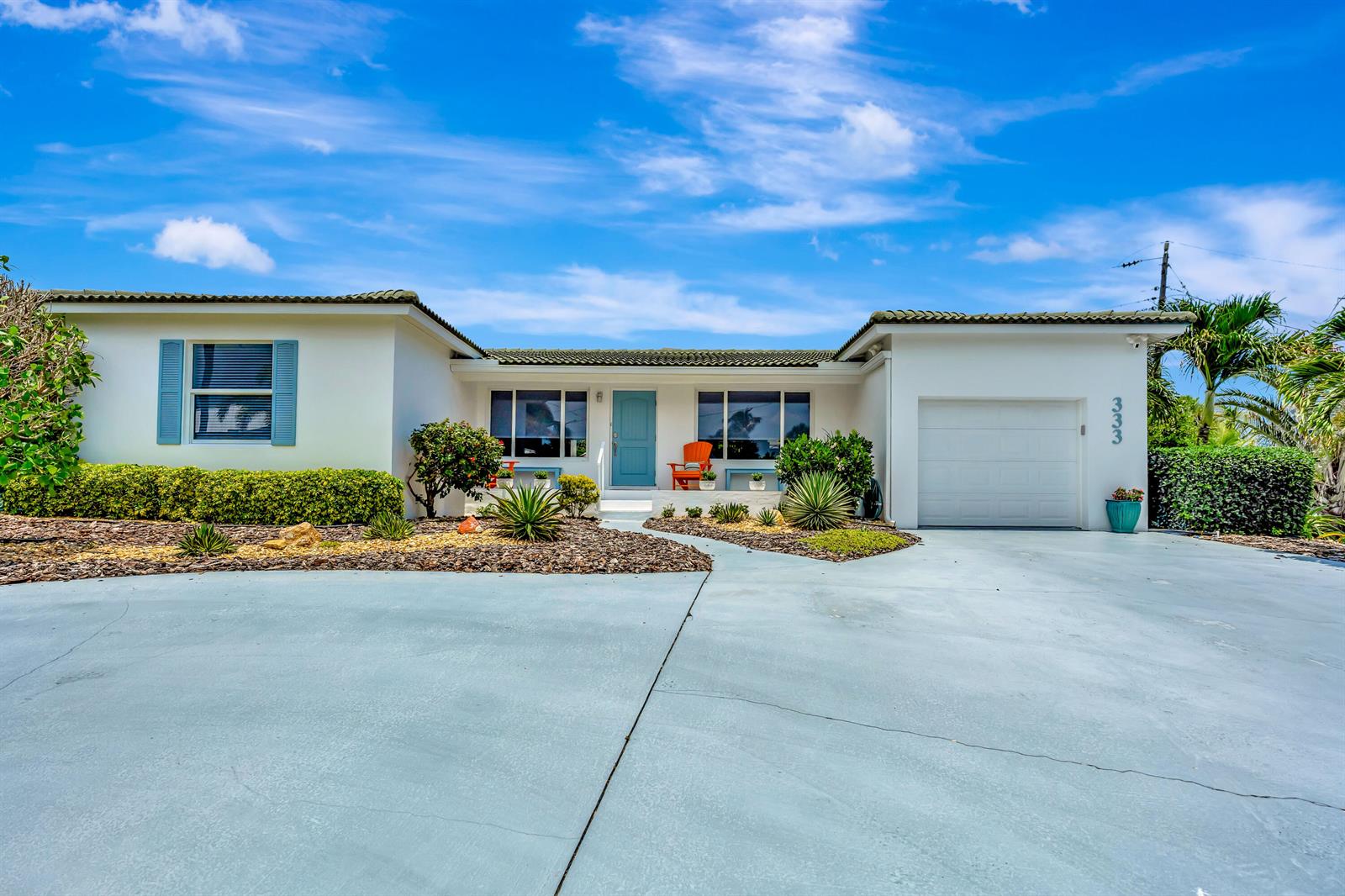 A single-story house with a white exterior, blue door, and a paved driveway — 333 Ocean Drive, Juno Beach FL 33408, JUNO BEACH, FL