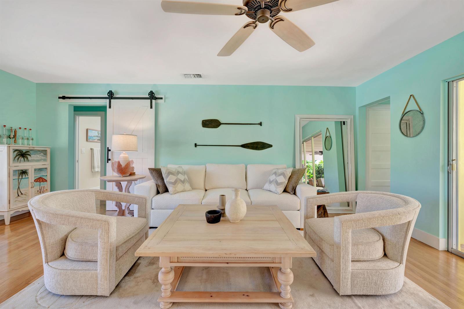 A living room features light blue walls, a white sofa, two armchairs, and wooden paddles — 333 Ocean Drive, Juno Beach FL 33408, JUNO BEACH, FL