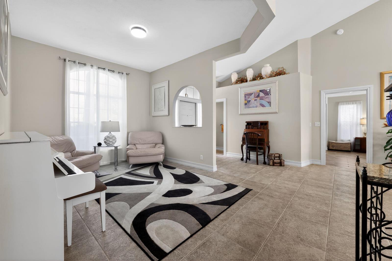 A living room features a white piano, a patterned rug, and tile flooring — 12301 Cabot Court, Boca Raton FL 33428, BOCA RATON, FL
