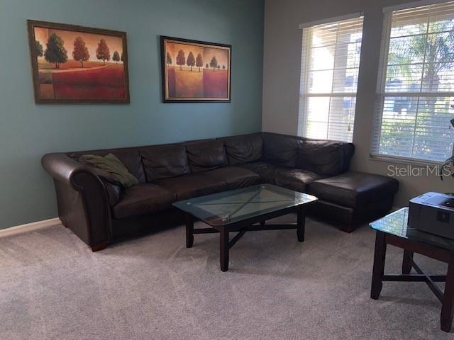 A living room features a large brown sectional sofa, a glass coffee table, and wall art — 842 SUSSEX DRIVE, DAVENPORT, FL