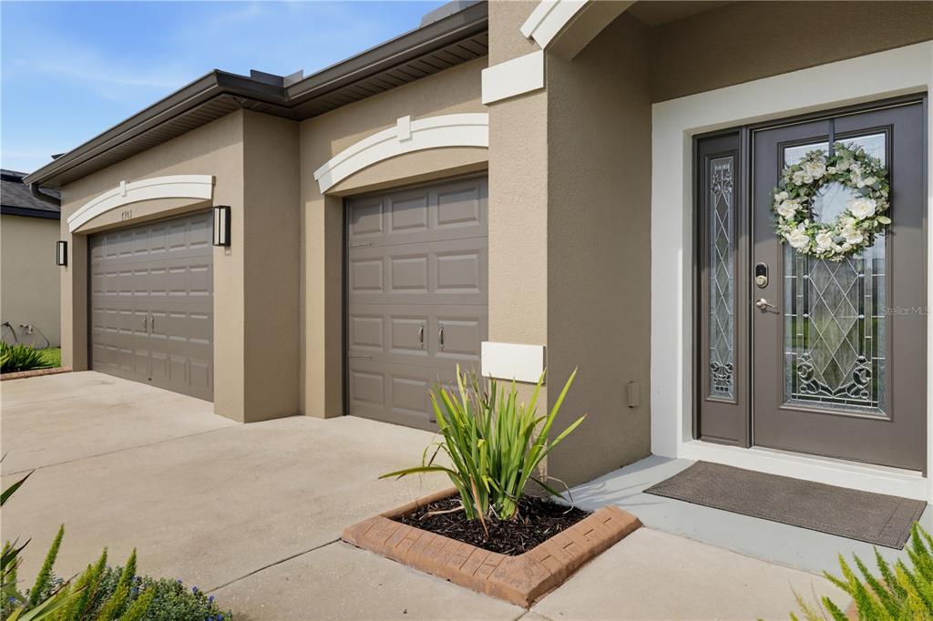 A view of a house exterior featuring a two-car garage and a front entryway door — 7903 LAGO MIST WAY, WESLEY CHAPEL, FL