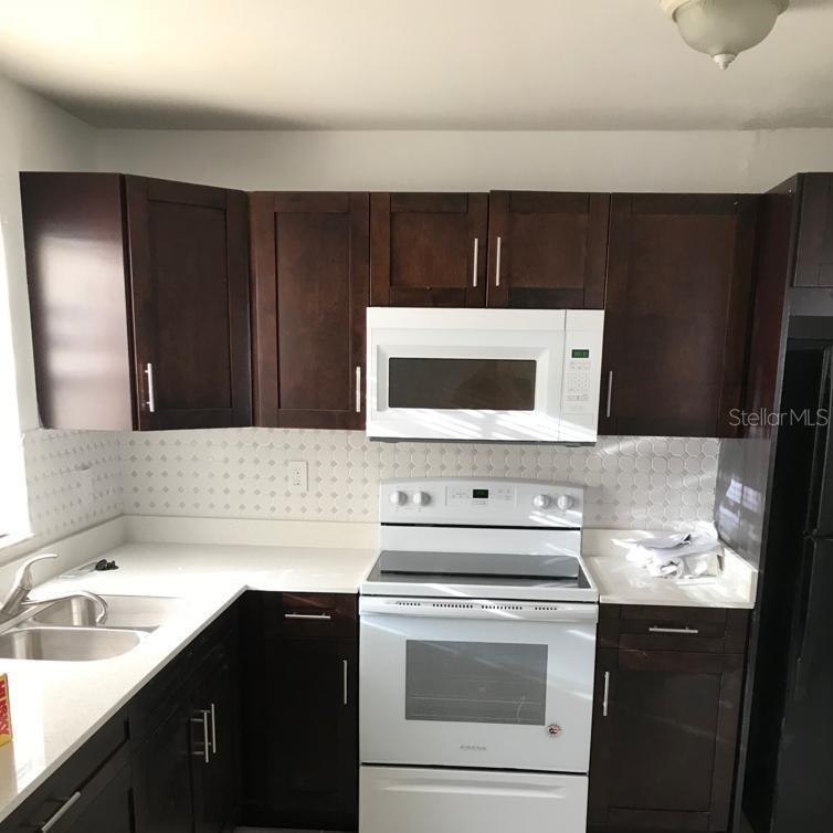 A kitchen featuring dark wood cabinets, white countertops, a white stove, and a microwave — 2400 NW 21ST STREET UNIT 3, FORT LAUDERDALE, FL