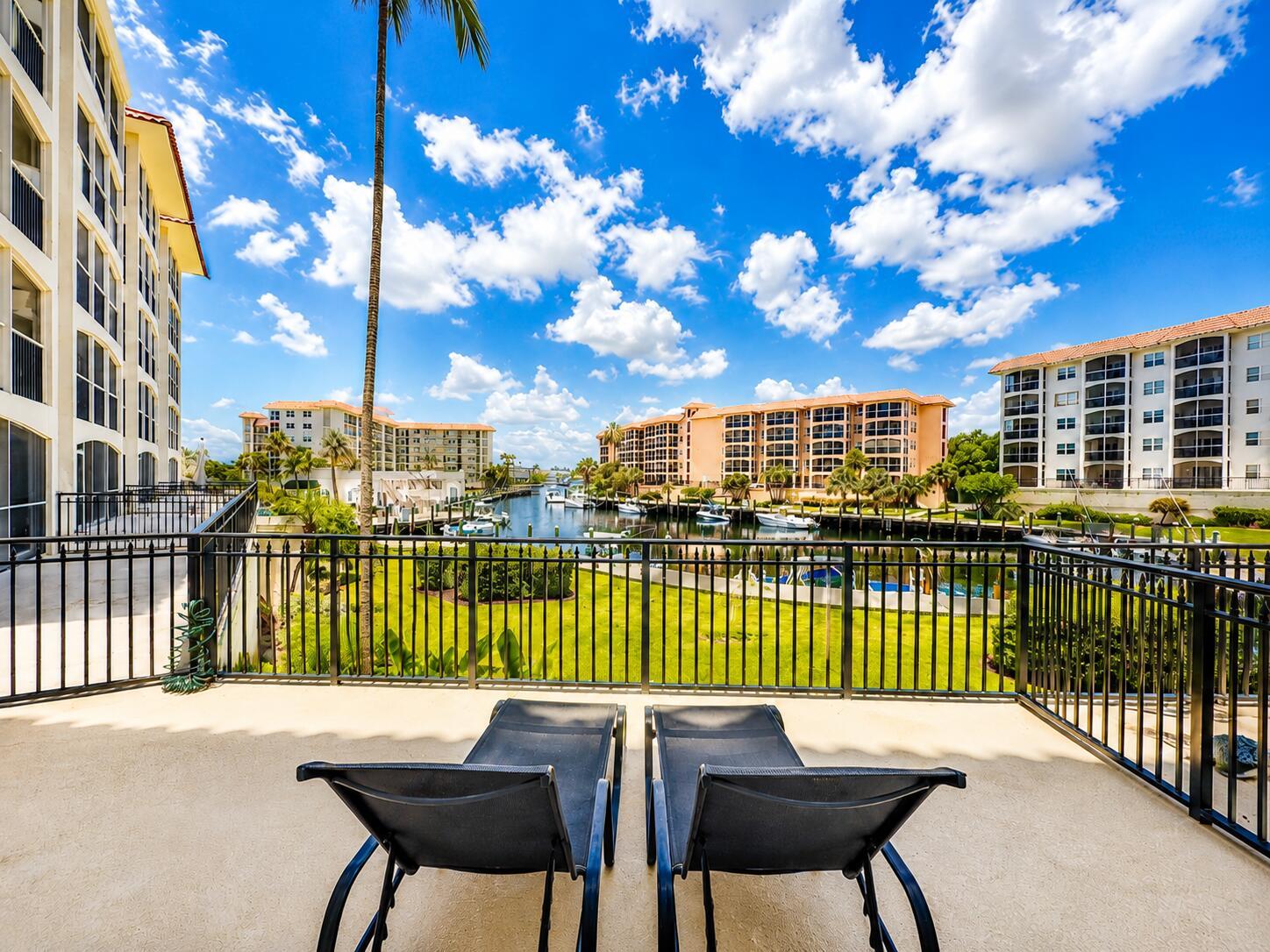 A balcony with two lounge chairs overlooks a canal between large apartment buildings — 2871 N Ocean Boulevard # M132, Boca Raton FL 33431, BOCA RATON, FL
