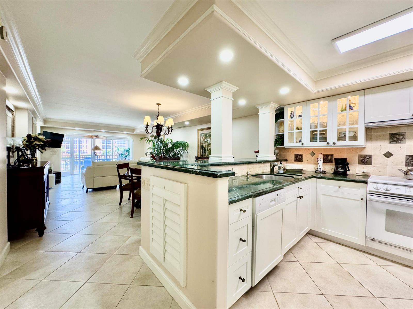 A kitchen with white cabinets and green countertops opens to a dining and living area — 2871 N Ocean Boulevard # M132, Boca Raton FL 33431, BOCA RATON, FL