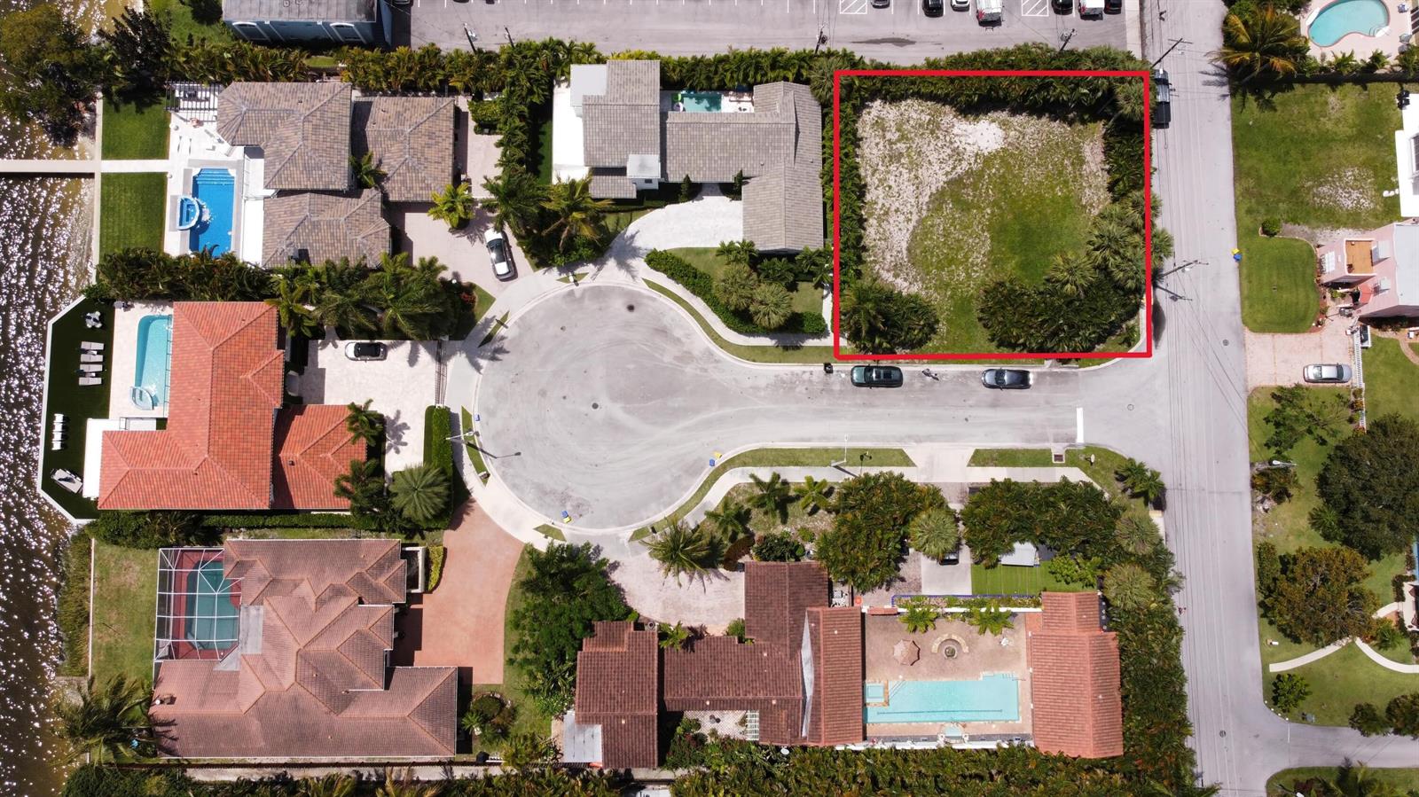 An aerial view shows a vacant, rectangular residential lot surrounded by trees and neighboring houses — 7 Lakeside Palms Court, FL 33460, FL