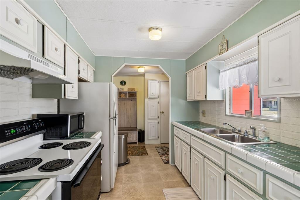 A kitchen features white cabinets, green tile countertops, a white stove, and a refrigerator — 14289 MIDFIELD STREET, BROOKSVILLE, FL