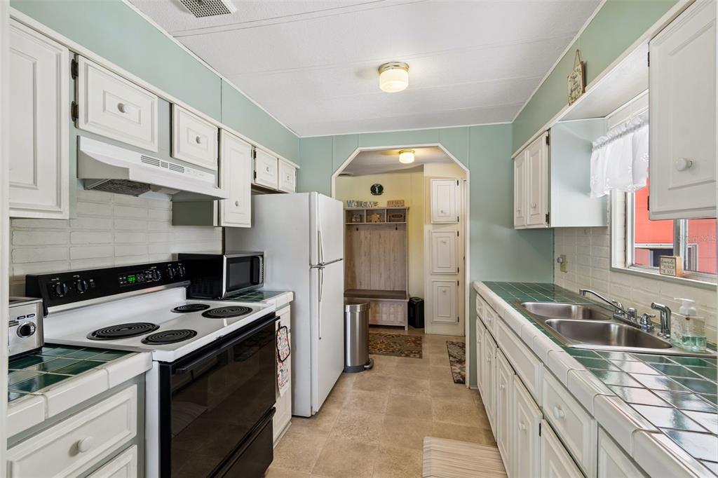A kitchen with white cabinets, green tile countertops, a white stove, and a refrigerator — 14289 MIDFIELD STREET, BROOKSVILLE, FL