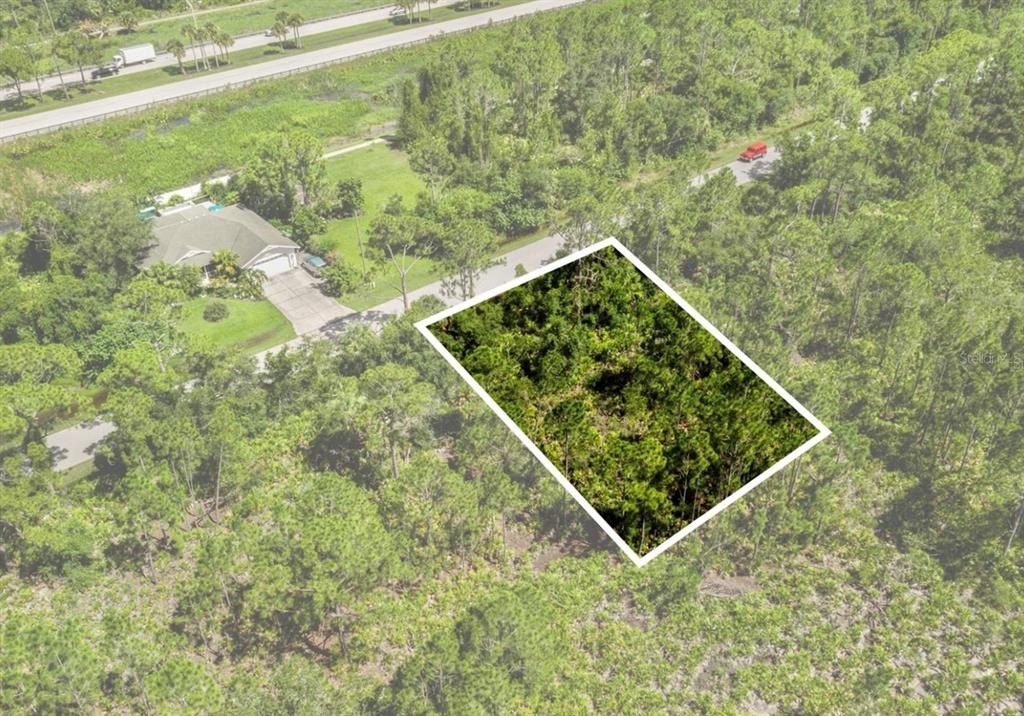 An aerial view shows a rectangular, wooded vacant lot outlined in white next to a house — 3319 VESSELS ROAD, PUNTA GORDA, FL